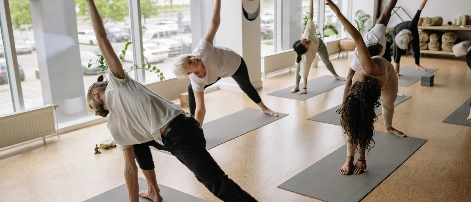A group class practicing Triangle Pose in a light-filled studio